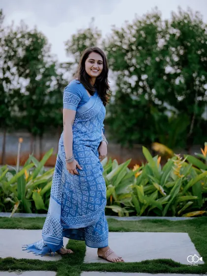 A beautiful solo portrait of the bride in a lovely blue printed saree, walking gracefully in a garden.