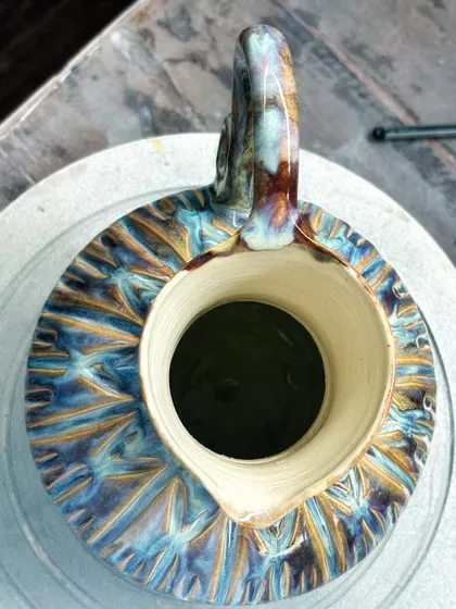 An overhead view of my multi-glazed pitcher, showing the rich texture and the way the colors pool inside the carved lines. The spout and handle are carefully sculpted to be both beautiful and functional.