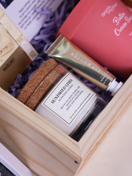 A close-up on the high-quality scented candle and Earth Rhythm beauty products included in the sister gift box.