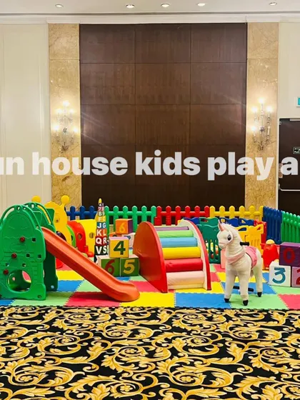 A detailed shot of the rainbow play area, focusing on the green climber with a slide and the rocking horse.