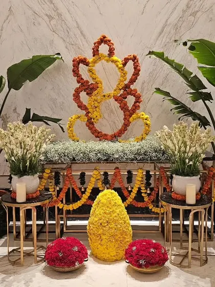 I create welcoming installations for corporate lobbies and entrances, like this elegant Ganesh decor for the Fairmont hotel. The design uses marigold flowers to form a traditional symbol, flanked by fresh plants and subtle lighting for a warm welcome.