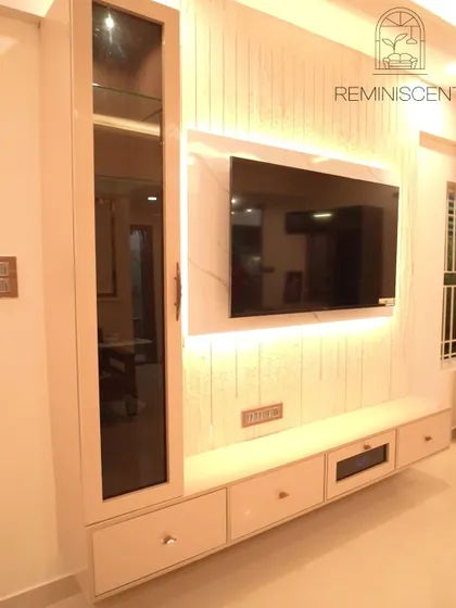 A sophisticated TV unit with a floating console and a back panel of vertical louvers and marble finish. The integrated lighting adds a warm, ambient glow.