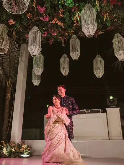A romantic dance under a ceiling of flowers and hanging lanterns. This setup creates an intimate and whimsical atmosphere for the couple's Sangeet night.