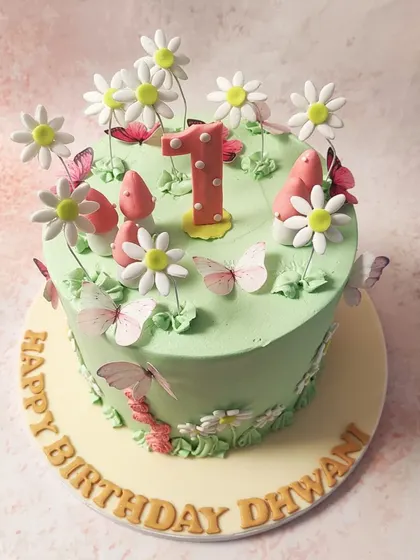 We create an enchanted forest for a first birthday with this magical fairy cake. A lush green canvas is home to whimsical mushrooms, delicate daisies, and fluttering butterflies, creating a storybook setting for a one-year-old's special day.
