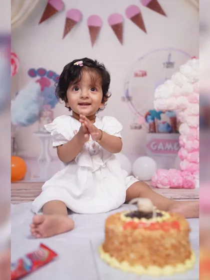 Before she dives into the cake, we capture a sweet portrait. This little girl is all smiles in her white dress, seated in front of her birthday cake in our Candy Land themed studio setup.