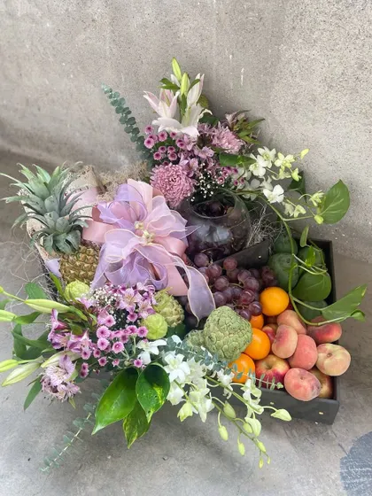 A bountiful fresh fruit hamper, elegantly arranged with an assortment of seasonal fruits and accented with delicate purple and white flowers. This is a healthy and beautiful gift option for any occasion.