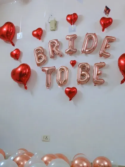 An angled view of the 'Bride to be' wall decor, featuring rose gold letters and red foil hearts.