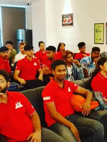 A group of students in red uniforms listening intently during a class session.
