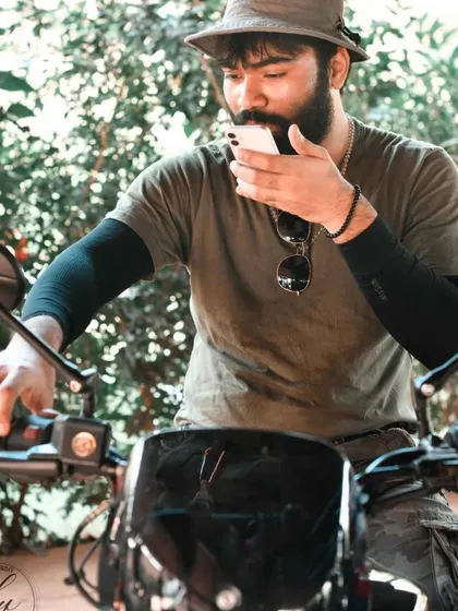 A stylish portrait of a rider checking his phone while seated on his bike. This image blends modern life with the classic biker aesthetic.