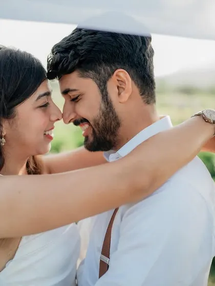 An intimate nose-to-nose pose under a white sheet. This creates a soft, dreamy, and private moment for the couple.