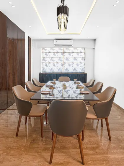 This formal dining space is designed for elegance and comfort. The 8-seater table is complemented by plush leather chairs, a statement chandelier, and rich wood paneling, creating a sophisticated ambiance for hosting.