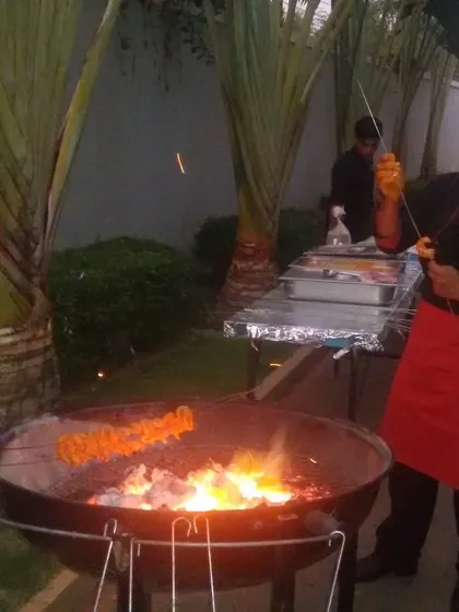 Nothing beats the aroma and flavor of food from a live tandoor. Our chef is seen here grilling succulent paneer tikka skewers over hot coals at an outdoor party. This service is perfect for adding a traditional and theatrical touch to weddings and social gatherings.