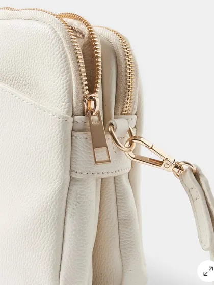 A close up detail of the zipper and clasp on the Australia Crossbody bag. The hardware is sturdy and has a beautiful polished gold finish.