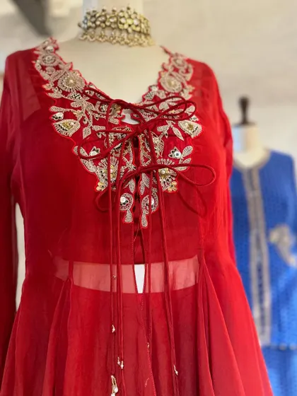 A close-up of a red peplum-style kurta with delicate embroidery and a tie-up detail at the neck. This is a modern, flattering silhouette for any festive occasion.