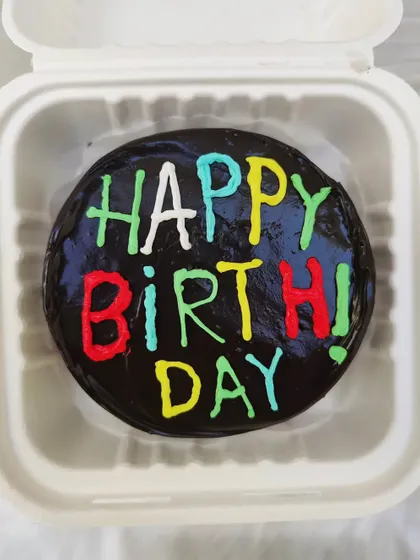 A rich chocolate truffle bento cake with colorful "Happy Birthday" lettering.