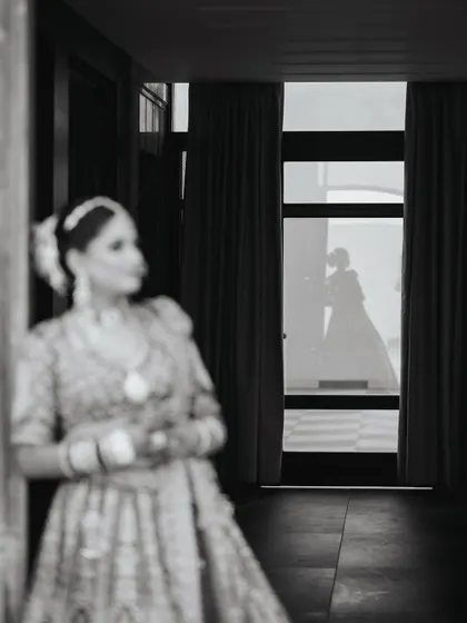 A creative shot using reflection to tell a story. The bride is out of focus in the foreground, while her sharp reflection is seen in the glass.