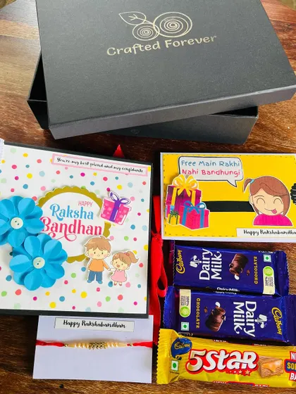 This is our classic Rakhi gift hamper, perfect for a brother. It includes a handmade album for your photos, a funny greeting card, a simple rakhi, and his favorite chocolates.