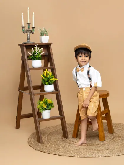 A charming smile from a dapper little boy. This classic portrait uses a simple, neutral background to highlight his adorable outfit and happy expression.