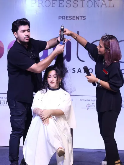 Working with an assistant on stage to demonstrate a blow-drying technique for maximum volume.