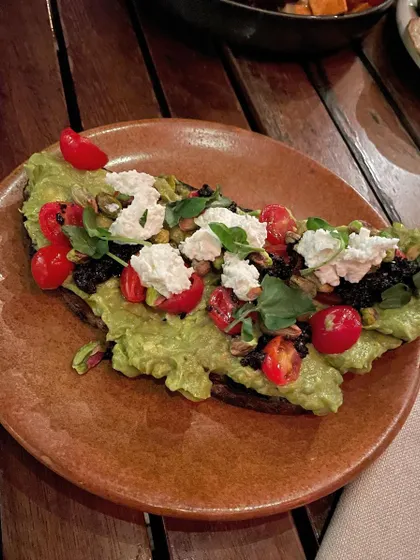 This is a wonderfully nourishing plate. Mashed avocado and cheese on a slice of sweet potato, topped with cherry tomatoes and greens. It's a great combination of healthy fats and complex carbohydrates.