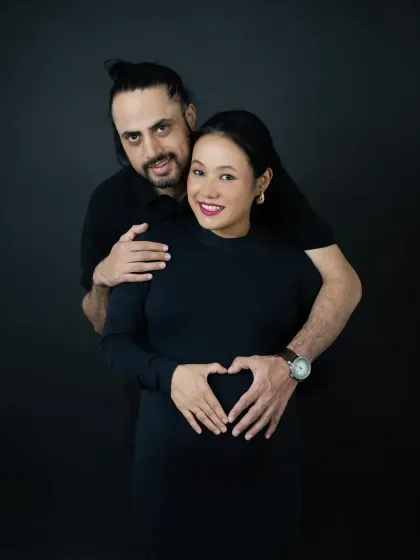 A classic pose with a modern feel. The couple creates a heart shape with their hands on the baby bump, a simple and sweet gesture of love.