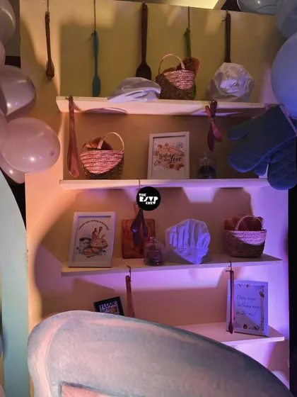 A shelf filled with baking-themed props like whisks, baskets, and framed art, adding to the bakery atmosphere.