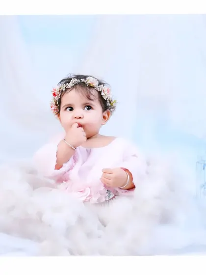 A little angel floating on a cloud. This dreamy studio setup with a floral crown and soft, fluffy clouds creates a magical and ethereal portrait.