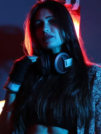 A striking portrait with headphones around my neck. The dual-tone lighting highlights a look of cool confidence, ready for any challenge the night brings.