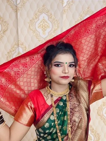 Posing with the red veil, this bride showcases a classic look with a green saree, red blouse, and simple, elegant makeup that highlights her features.