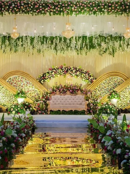 For a truly elegant reception, I designed this magnificent stage featuring cascading white flowers, sparkling chandeliers, and a stunning floral backdrop with gold-accented panels. This premium stage design is perfect for a grand wedding celebration.