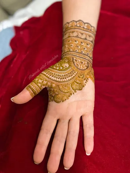 The design is extended to the thumb with detailed filler work. This shows how to seamlessly integrate finger designs with the main pattern on the hand.