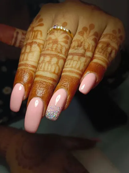 A different angle of the lovely peach and glitter bridal nails, showing how they complement the client's ring and mehendi.