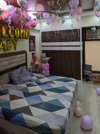 A full view of the decorated bedroom, showing the 'Welcome Baby' balloons on the wall and ceiling, creating an immersive celebratory space.
