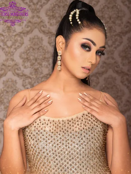 A golden goddess look. This style features a dramatic smokey eye, a sleek high ponytail, and a shimmering gold top, perfect for a night out.