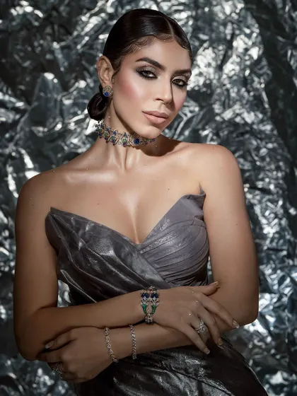 A glamorous shot focusing on the interplay between the metallic dress, the sparkling jewelry, and the glowing skin.