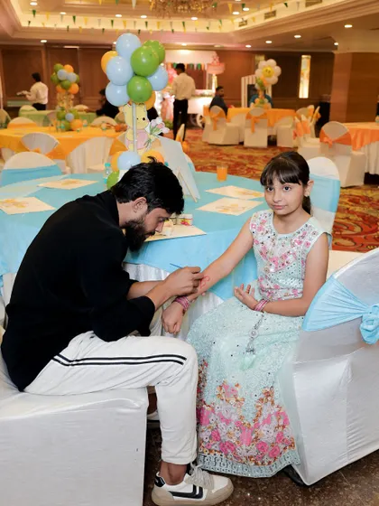 A young guest getting her arm painted at a face and body art station during a Winnie the Pooh themed party.