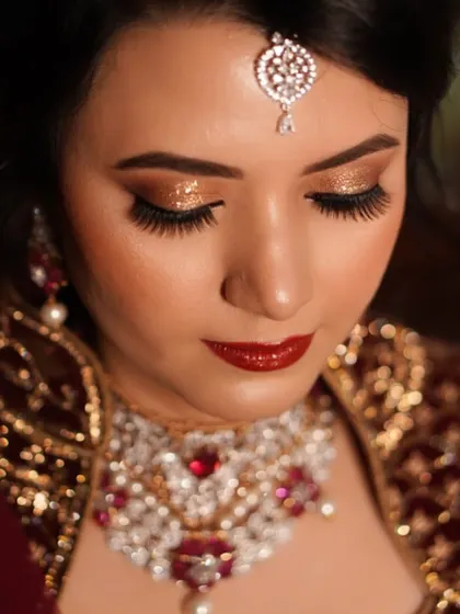 A close-up of a classic combination: bold golden glitter on the lids paired with a rich, glossy red lip. This look is the epitome of confidence and timeless bridal glamour.