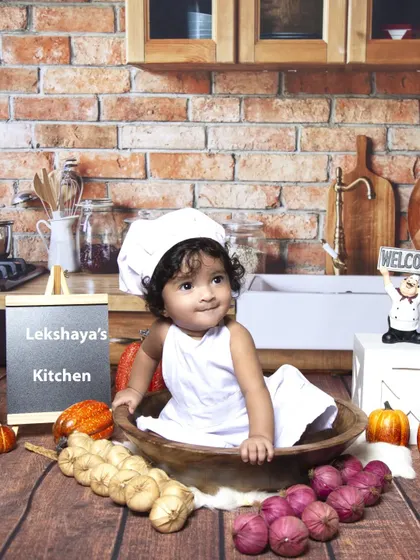 A fun and unique chef-themed sitter session. Dressed in a little chef's hat, this baby is the star of her own kitchen, complete with a brick wall backdrop and cooking props.