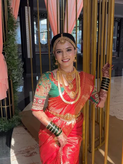 A beautiful portrait of the glowing bride, Priya. Her makeup features defined eyes and a bright lip, perfectly complementing her red saree.