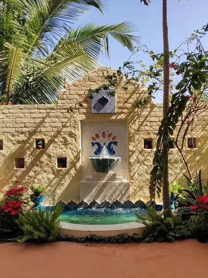 This backyard features a custom-built wall with an integrated water fountain. The combination of stone cladding, mosaic art, and the gentle sound of water creates a peaceful and artistic focal point.