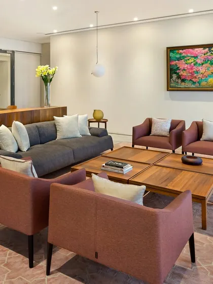 This living area in the Limestone Residence uses a palette of warm, earthy tones. The combination of a grey sofa and rust-colored armchairs creates a welcoming and comfortable atmosphere.