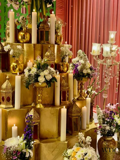 A closer view of the candle installation, showing the mix of pillar candles, golden lanterns, and small floral arrangements.