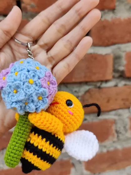 Holding the bee and flower keychain to show its size.