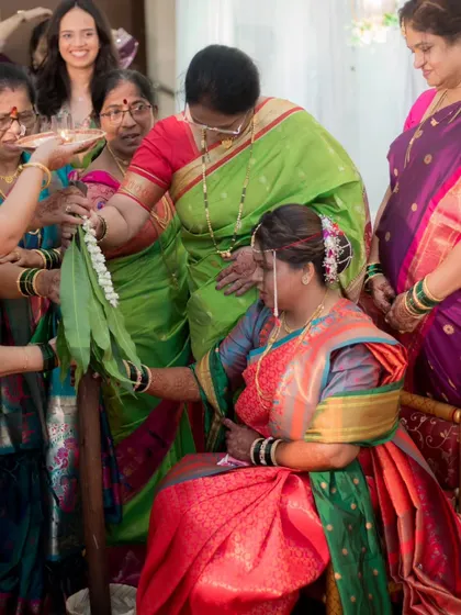 A photo capturing a traditional ritual during an engagement ceremony, where female relatives bless the bride-to-be.