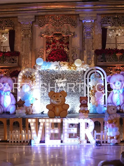 A royal and opulent take on the teddy bear theme. The stage is set against a grand, palace-like wall, with large teddy bear props, a sequin backdrop, and marquee letters spelling 'VEER'.