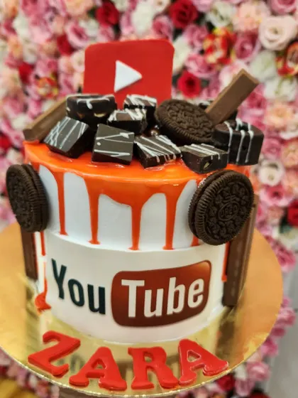 A YouTube-themed cake, perfect for an aspiring content creator. It's topped with edible chocolate bars and Oreos for an extra treat.