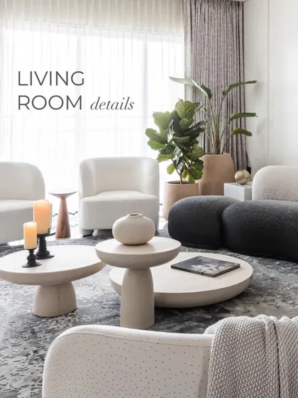 An overview of the living room details, showing how the curved white and black sofas, stone coffee tables, and a large fiddle-leaf fig plant come together. The space is a testament to how bold, geometric forms can still feel soft and inviting.