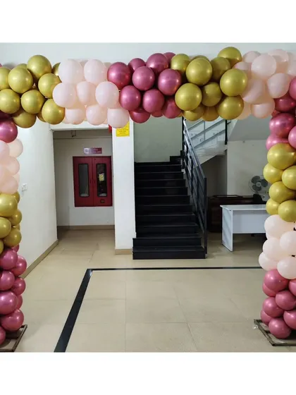 Another view of the pink and gold balloon arch, showcasing its sturdy construction and placement in an indoor hallway. This decor effectively frames the entrance to the main event area.