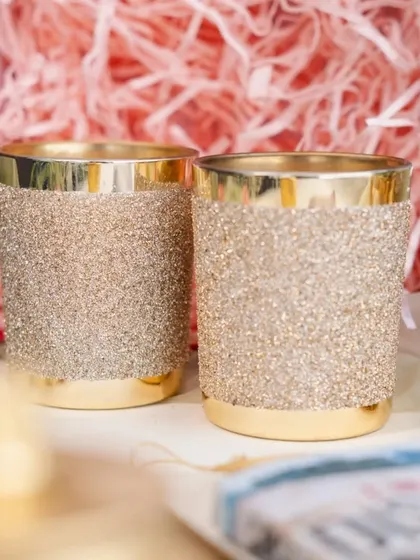 These golden glitter candle jars are a glamorous option for wedding favors or party decor, available for bulk orders.
