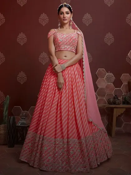 A gorgeous pink lehenga designed for twirling. The striped pattern on the skirt is complemented by a beautifully embroidered border and a modern off-shoulder blouse, making it ideal for a daytime wedding event.